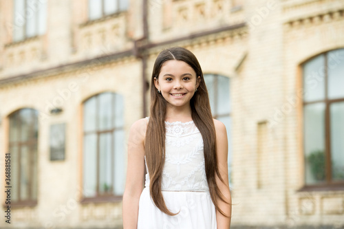 Happy child long hair smiling face urban background outdoors, childrens day concept