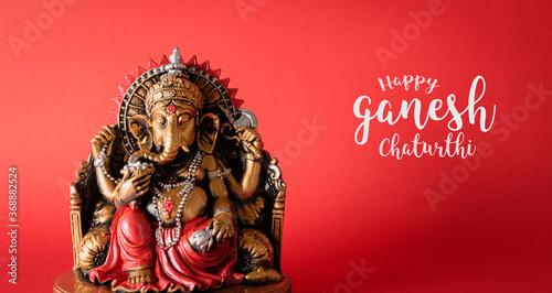 Photo Happy Ganesh Chaturthi festival, Bronze Ganesha statue and Golden texture with flowers, Ganesh is hindu god of Success