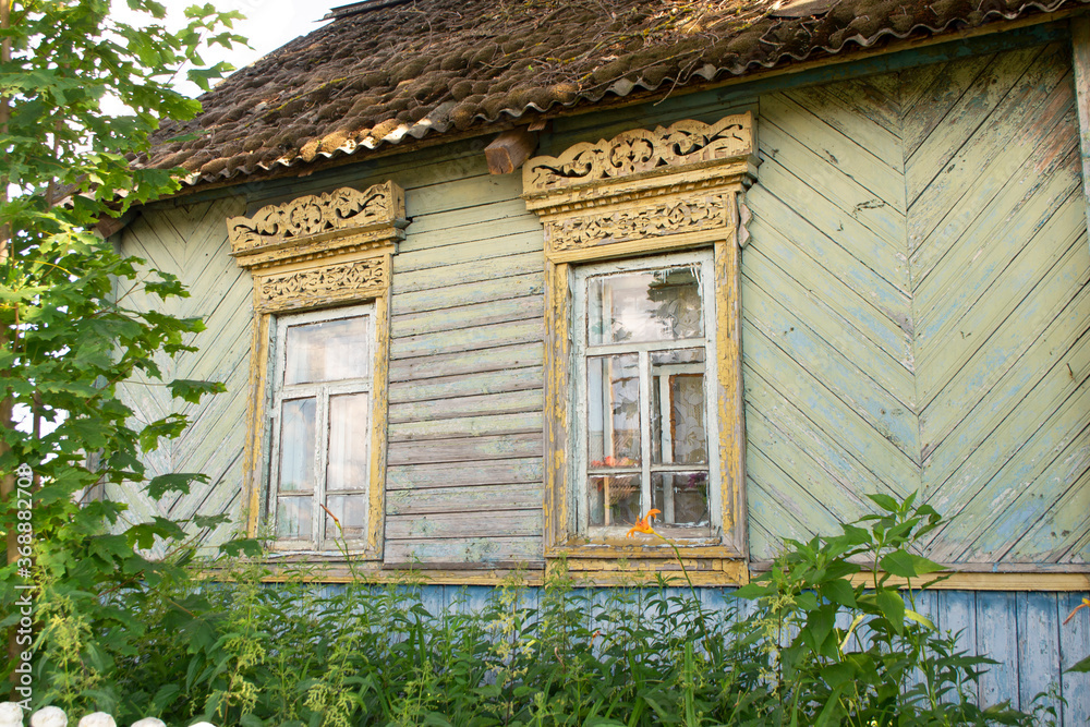 Old wooden shabby house in Belarus. Windows and bushes