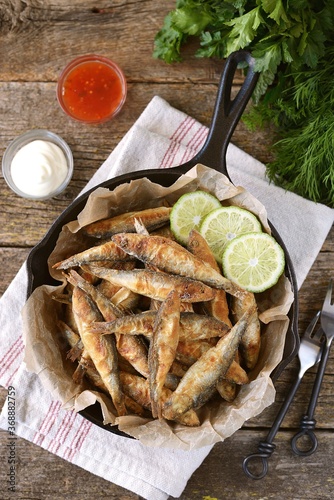 Grilled little fish in cornmeal and lime. On an old wooden background.