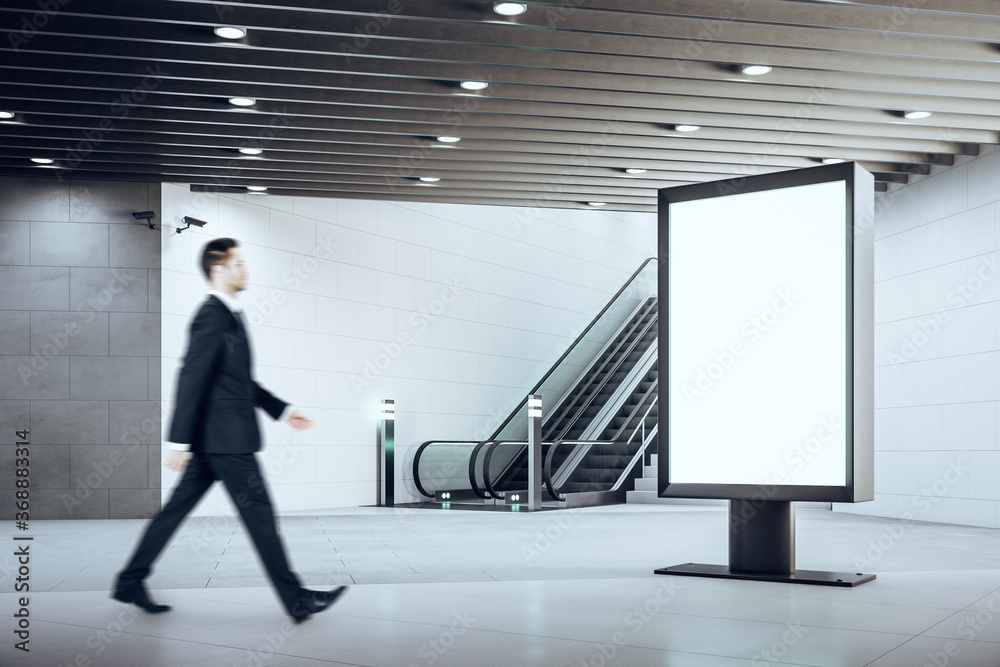 Fototapeta premium Train station interior with businessman climbing escalator