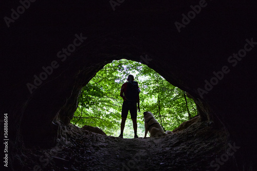 man and dog silhouette at the entrance of a cave