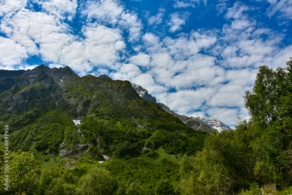 Obraz premium View of the beautiful countryside of North Ossetia. Sunny day. Beautiful summer landscape in the mountains. Grassy fields and hills. Rural landscapes