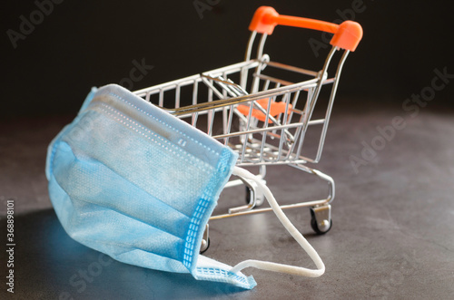Shopping cart with protective medical mask against Covid19 and online shopping on quarantine concept.