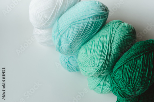 acrylic soft pastel green, azure and white colored wool yarn thread skeins row on white background, top angle view, horizontal stock photo image with copy space for text