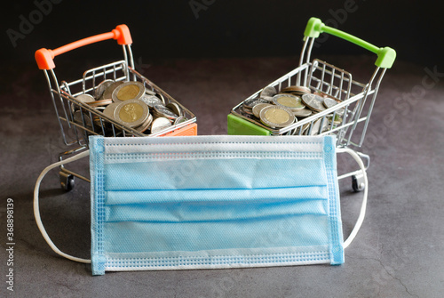 Shopping cart with thai baht coins protective medical mask against Covid19 and online shopping on quarantine concept.