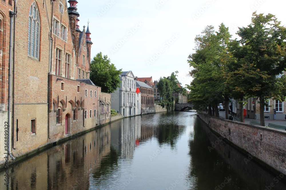 Ciudad de Brujas con un canal que pasa al costado de las casas con arboles al otro costado