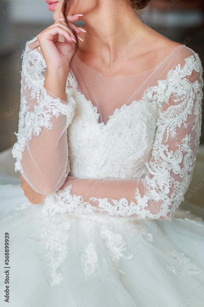 The torso of a bride in a white wedding dress,