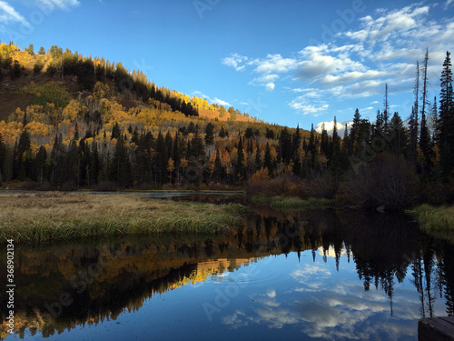 Beautiful fall mountain reflection on the lake with blue sky and clouds in the background. 