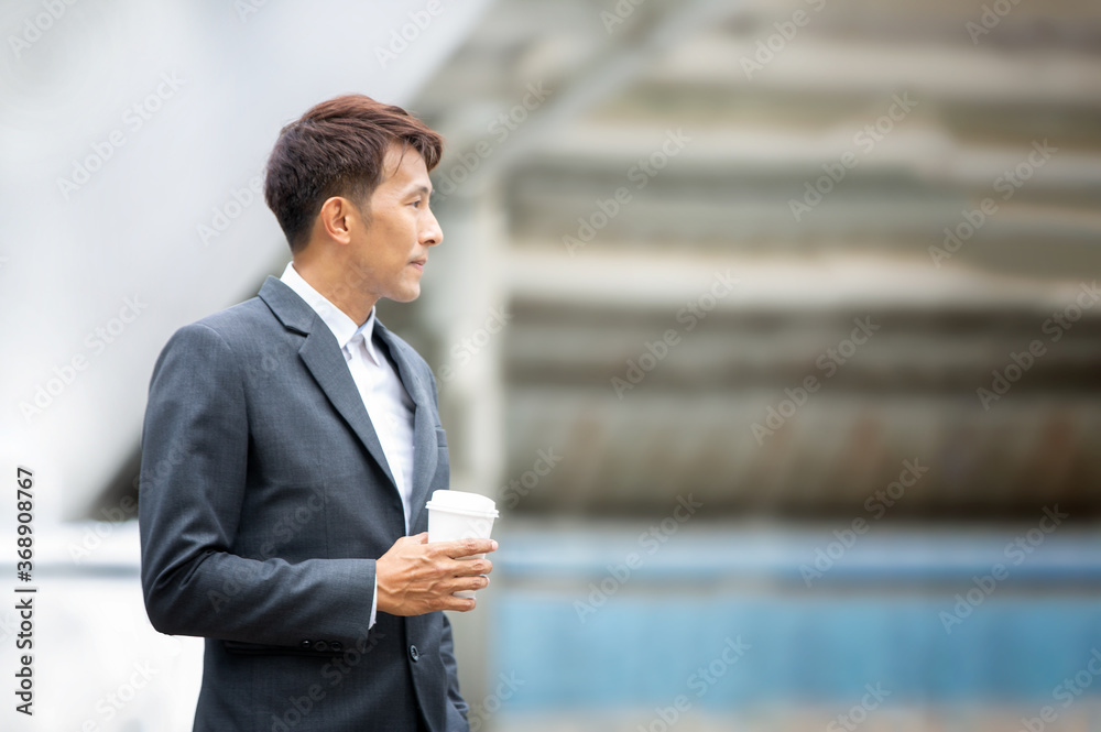 Side view of young businessman standing with coffee cup at outdoor Side view of young businessman standing with coffee cup at outdoor