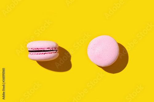 Pink macaroon on yellow colored background, colorful french cookie macaron. photo