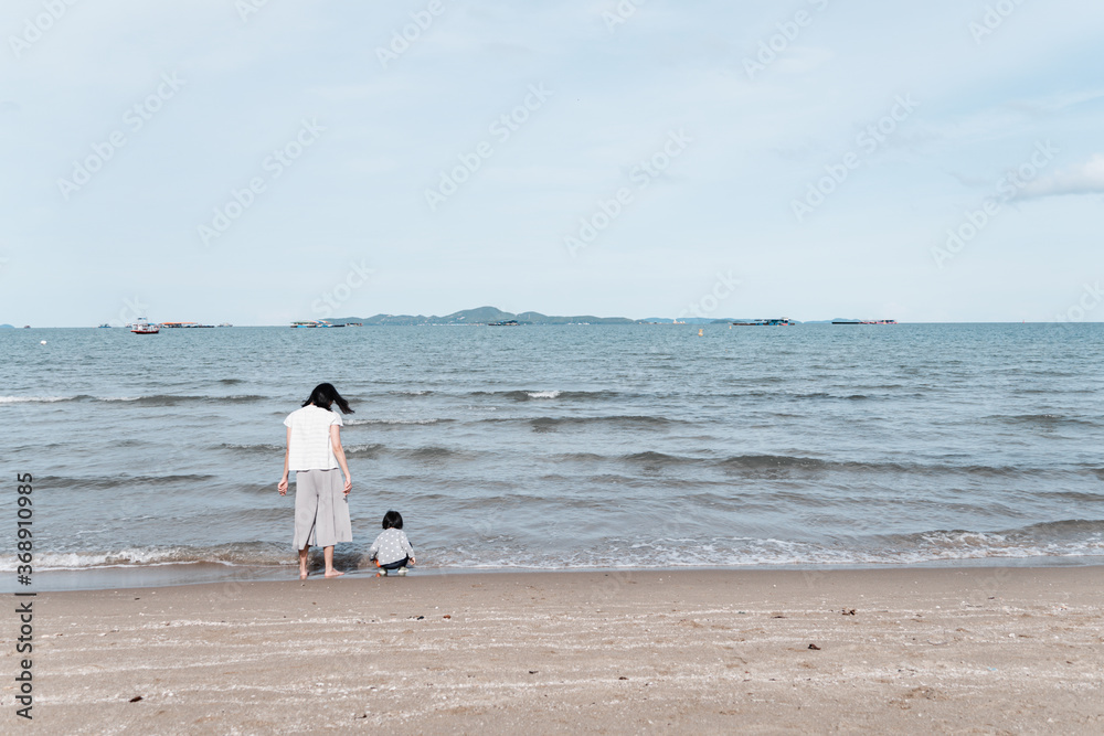 Mother and 3 years old asian kid walking on the beach. Background for family vacation and recreation. Mother and 3 years old asian kid walking on the beach. Background for family vacation and recreation.