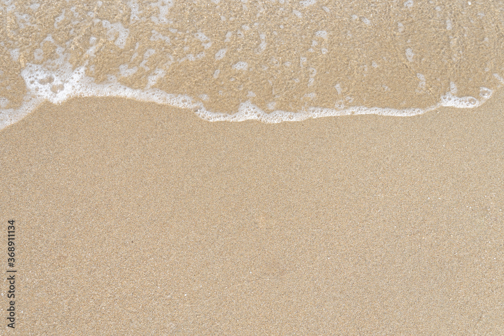 Close up ocean wave bubble on sandy beach. Background for vacation holiday and natural feeling.