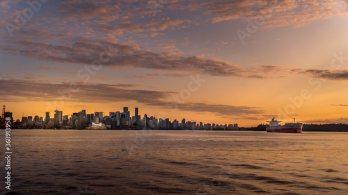 Sunset over the Skyline of Downtown Vancouver with a Ocean Freighter moored in the harbor. Viewed from a Harbor Cruise ship in the Vancouver Harbor