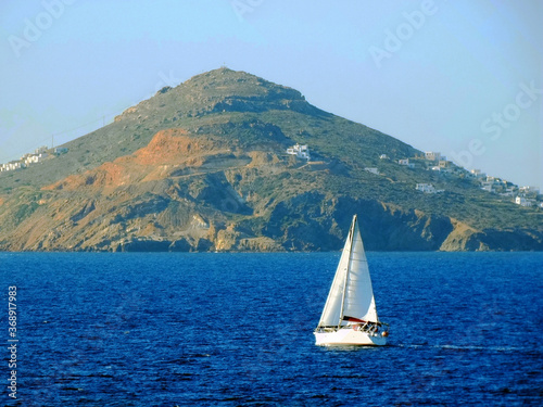 Tourists sail a yacht near the coastline of Paros Island in Aegean Sea in Greece. Paros located at the heart of the? Cyclades, one of famous Greek travel destinations for tourism and vacation.