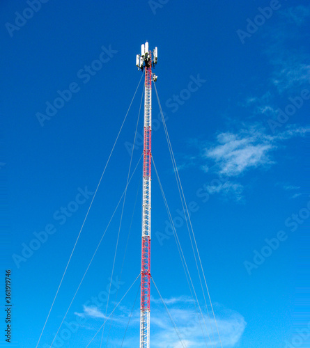 high mobile telecommunications tower and 5G stretching into blue sky photographed from ground