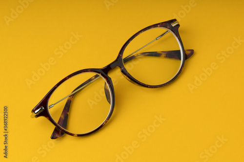  Glasses with transparent optical lenses on yellow background close up