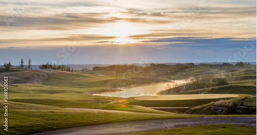 Golf Course Early Morning with Steam over Pond While Sun rises 