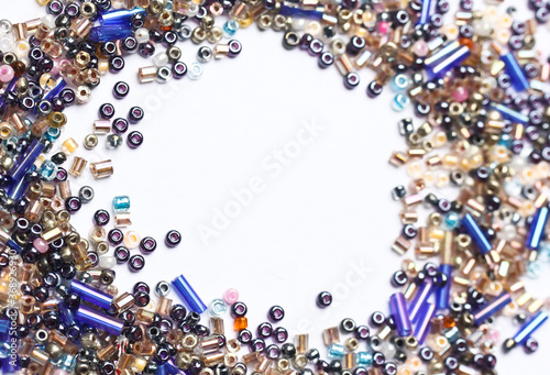 small indian beads of different shapes in the form of a vignette lies on a white background