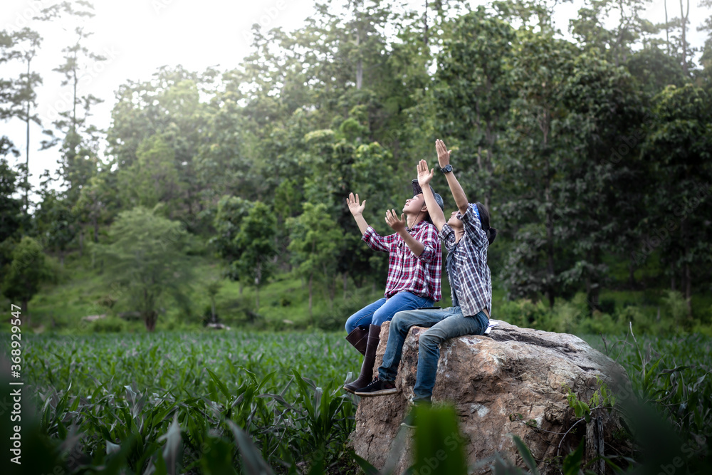 Two young male hands raised and praying in corn field. belief of agriculture concept. Two young male hands raised and praying in corn field. belief of agriculture concept.