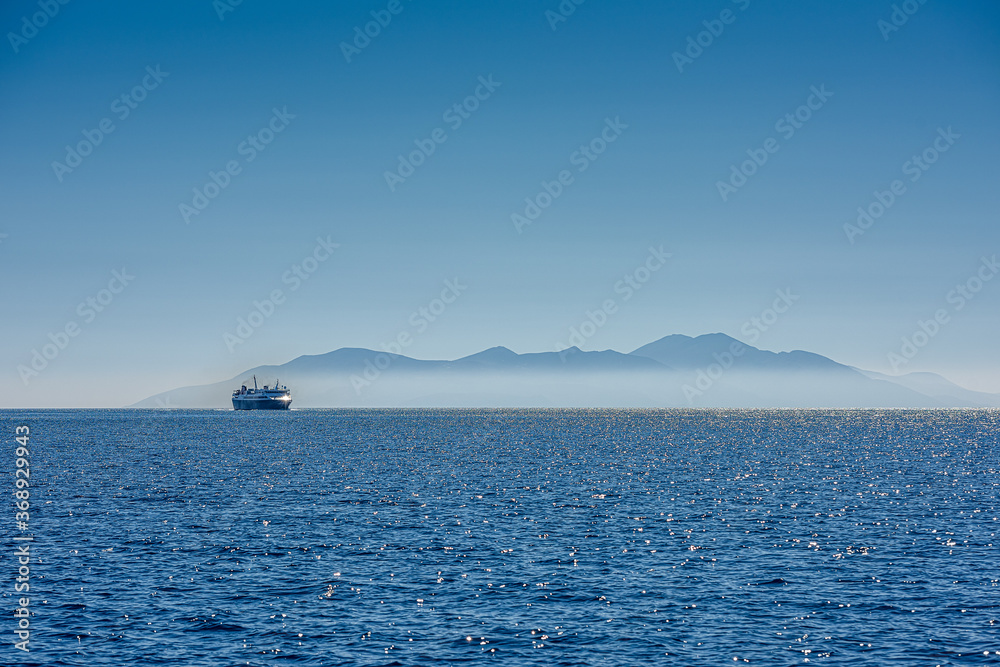 ferry ship in front of a greece island in the mist - obrazy, fototapety, plakaty 