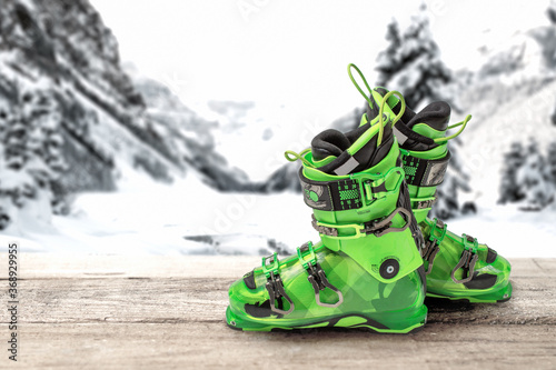ski boots on a wooden table against the background of mountains. bright green sports ski boots photo