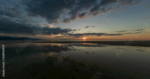 Time lapse: Sunset view on the ocean with reflection and silhouette. A beached foreground log adds interest. Slow motion timelapse 4K footage. Shot at 2160p.