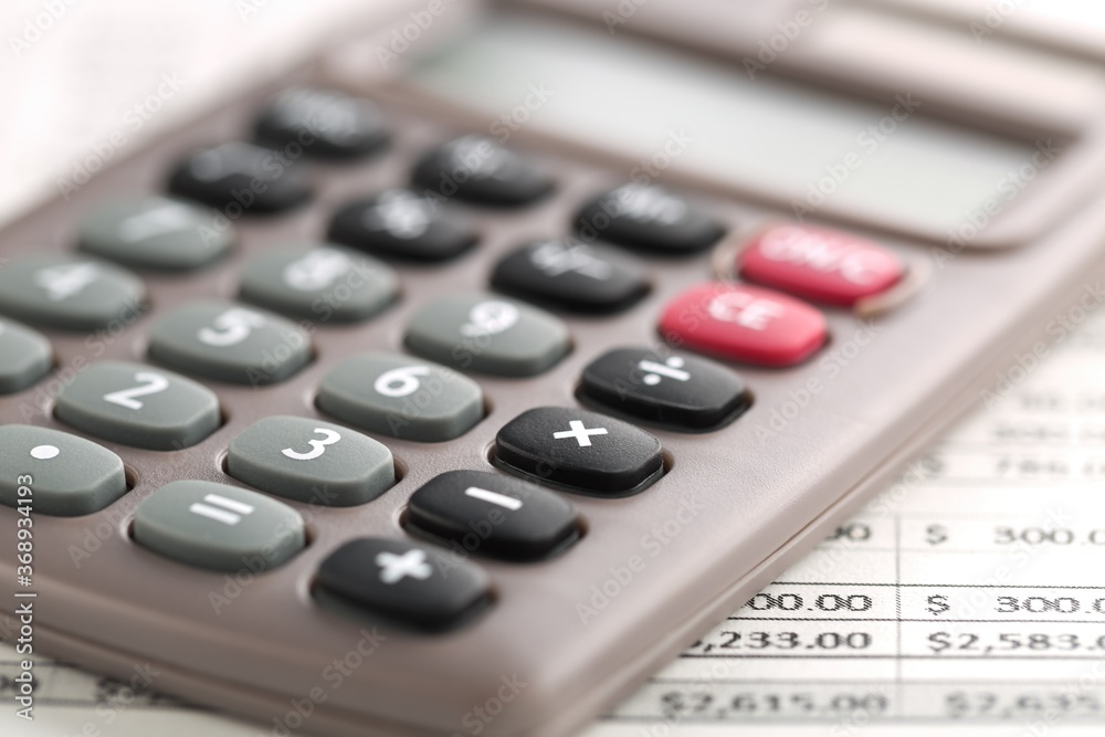 Pocket calculator on financial analysis sheet background - tax, finance or accounting concept Pocket calculator on financial analysis sheet background - tax, finance or accounting concept