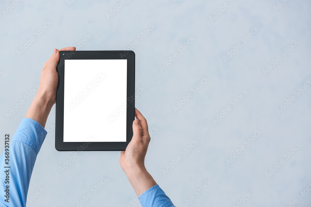 Hands with modern tablet computer on grey background