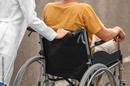 Doctor and young man in wheelchair outdoors