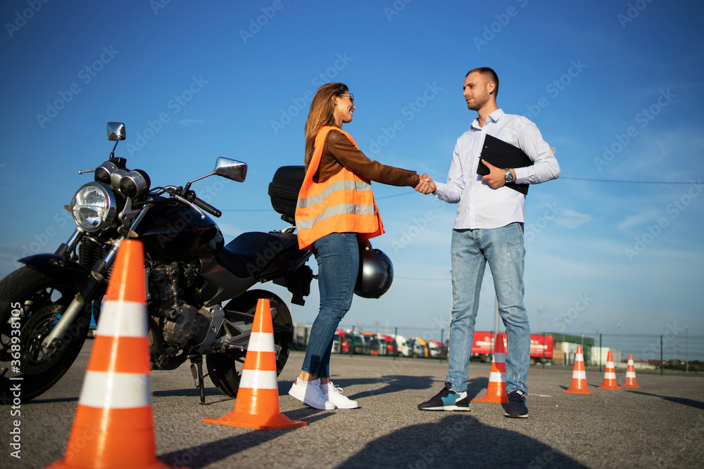 Motorcycle driving school. Instructor and student handshake before start of the classes. Safe ride lessons for motorcycle driving.