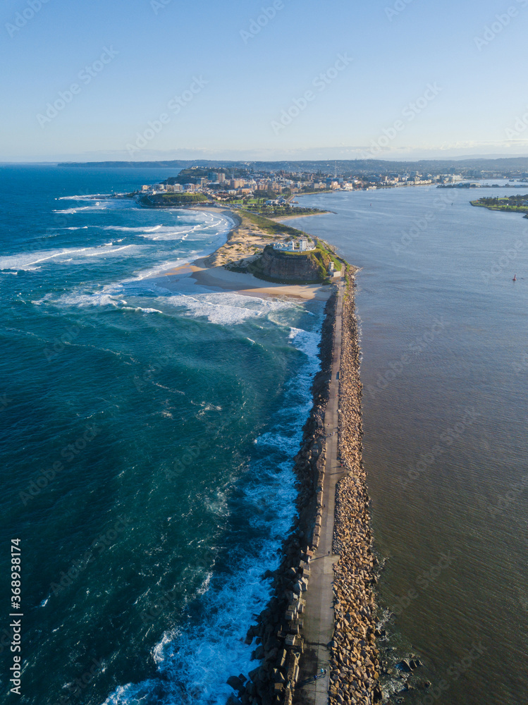 Aerial view of Nobbys lighthouse and Newcastle skyline from above the breakwall.