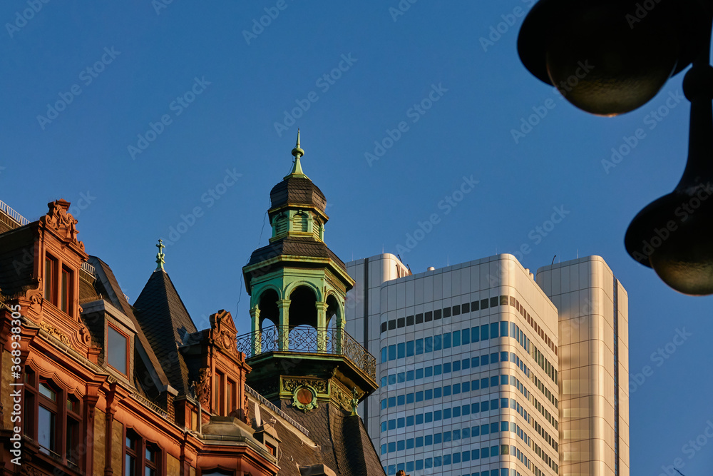 Modern skyscraper of the German railway behind the playful facades and towers of the old houses of Frankfurt