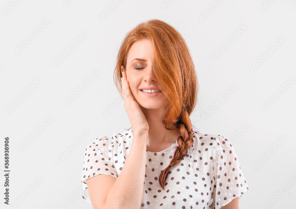 Beautiful young redhead woman on light background