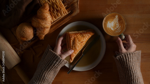 Female having breakfast with freshly bakery and latte coffee on wooden table