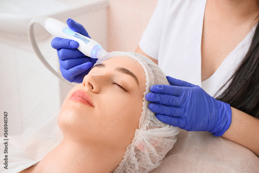 Woman undergoing procedure of vacuum hydro peeling in beauty salon