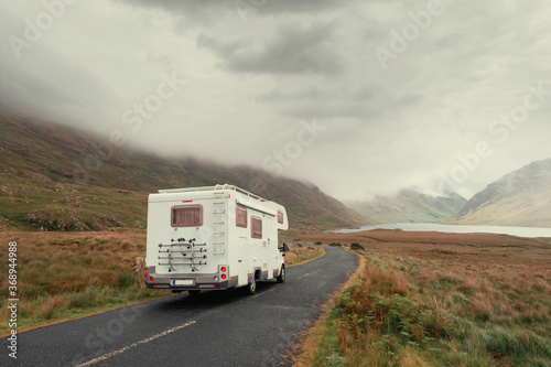 Motor home on a small asphalt road into mountains, Connemara region, Ireland, Low cloudy sky. Concept active travel holiday.