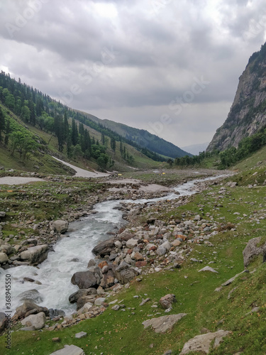 Beautiful river stream flowing through rocks in an epic Indian Himalayan Mountain Valley.