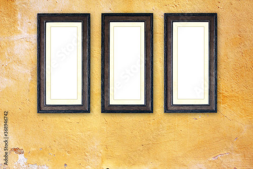 Three empty picture frames on old stucco wall