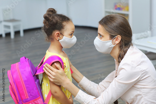 a light skinned female talking to a dark skinned student with medical masks