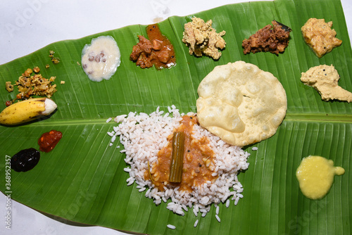 Kerala Onam sadhya, boiled rice with many curries Parippu, Sambar, dessert Payasam on banana leaf . traditional vegetarian feast on Onam, Vishu festival South India. Top view spicy Indian veg food photo