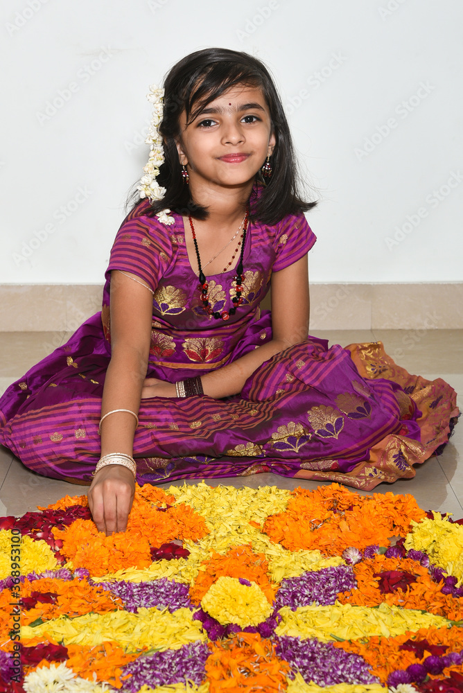 Kerala Onam festival, happy young Indian girl child, wearing traditional dress putting flower