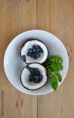 Сoconut in a plate with mint and blueberries