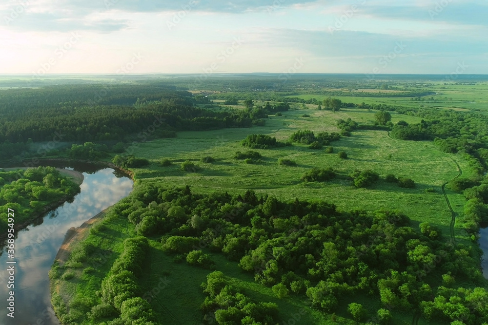 Flying over bend of the river and forest on island inside it in natural beautiful wild landscape. Aerial view of picturesque background, aerial panoramic view of natural park at sunny summer day.