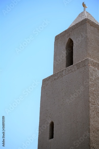 low angle view on old stone minaret by blue sky photo