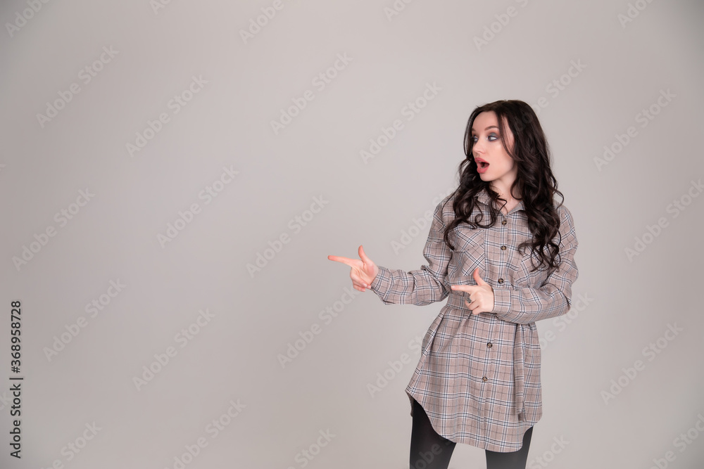 Beautiful girl student, business woman smiles, pointing and looking away over gray background Beautiful girl student, business woman smiles, pointing and looking away over gray background