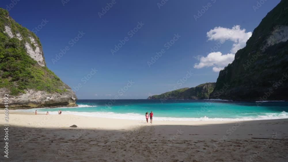 Happy couple enjoy honeymoon vacation on Kelingking Beach in Nusa Penida on background amazing nature landscape. Popular travel destinations active lifestyle travel tourist on Bali Indonesia. 4K Happy couple enjoy honeymoon vacation on Kelingking Beach in Nusa Penida on background amazing nature landscape. Popular travel destinations active lifestyle travel tourist on Bali Indonesia. 4K