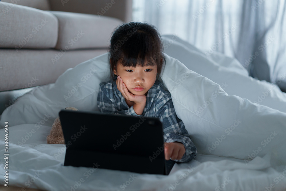 Asian Little girl using tablet digital under blanket in bedroom at night
Asian Little girl using tablet digital under blanket in bedroom at night