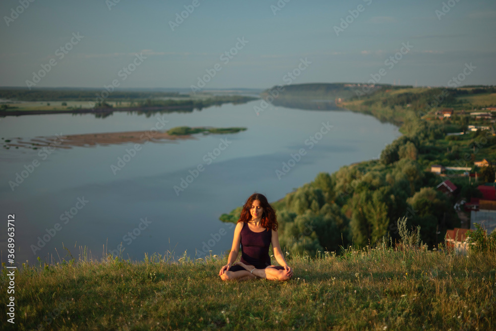 Yoga practice and meditation in nature in sunrise. Woman practicing near big river Kama.