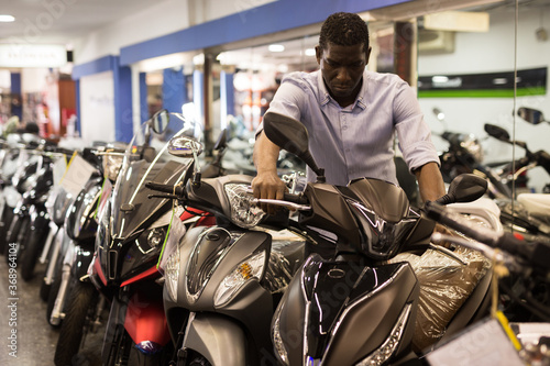 Afro american man is shopping and choosing new motobike in moto store. High quality photo